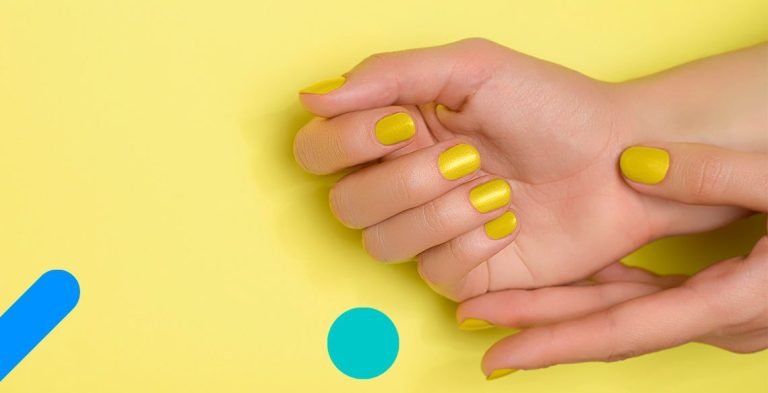 Mão com unhas pintadas de amarelo sobre fundo amarelo