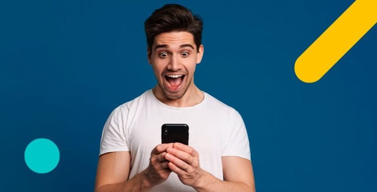 Homem sorrindo segurando celular nas mãos